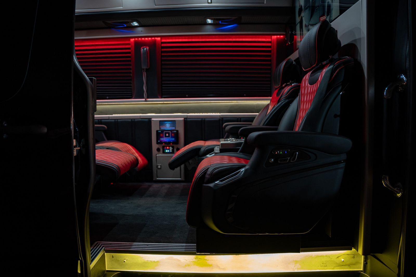 Interior of a luxury Sprinter van with quilted red and black leather captain's chairs